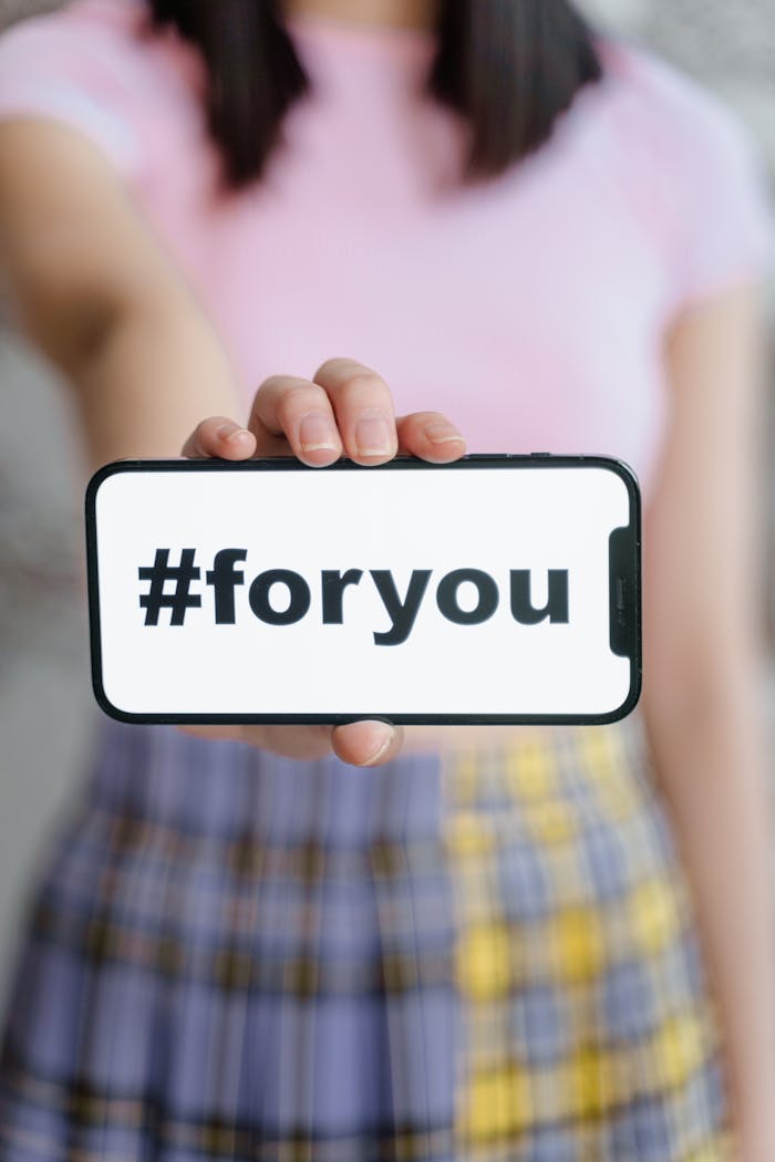 services-04 A person holding a smartphone with the hashtag #foryou on the screen, selective focus.